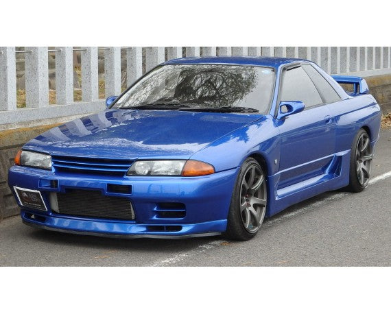 Front side view of a blue Nissan Skyline R32 with aftermarket body kit and alloy wheels