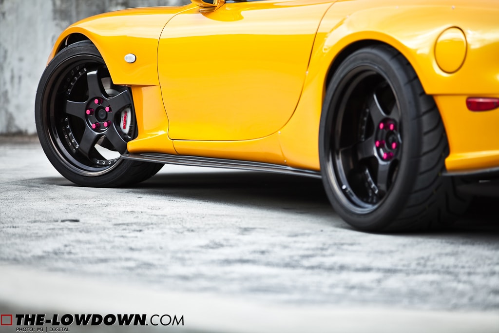 Low angle close-up of yellow Mazda RX-7 FD3S with JSAI Aero side skirts installed aftermarket body kit detail