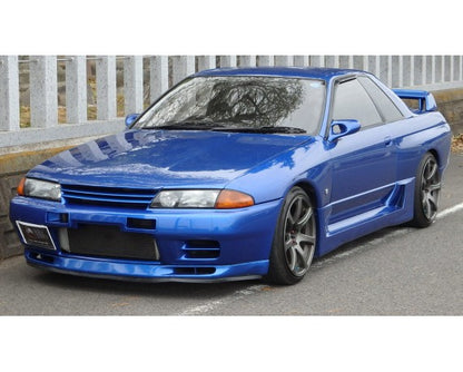 Front side view of a blue Nissan Skyline R32 with aftermarket body kit and alloy wheels