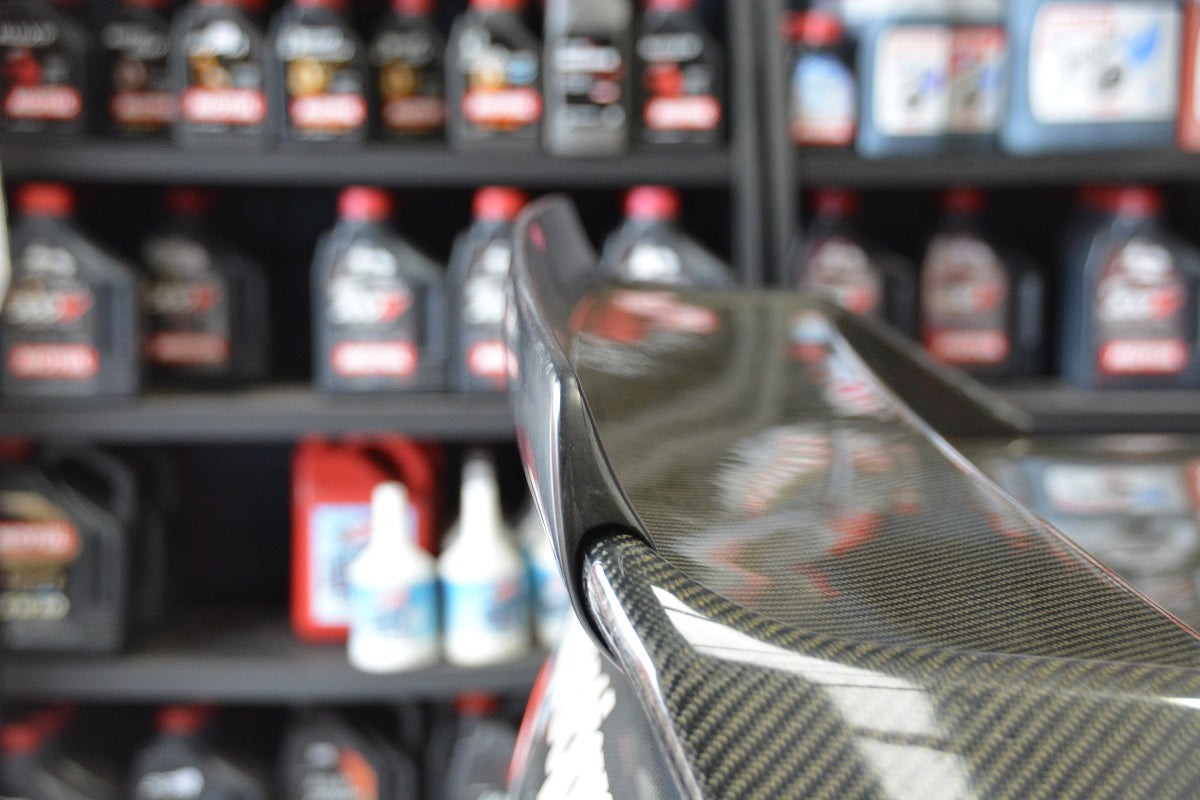 Close-up of a carbon fibre rear wing spoiler for a performance car with glossy finish