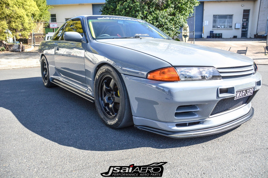 Front angle view of a grey Nissan Skyline R32 with JSAI Aero front lip, side skirts, and black wheels