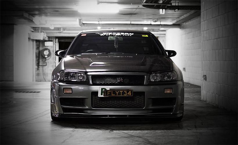 Front view of Nissan Skyline R34 GT-R with aero body kit in garage