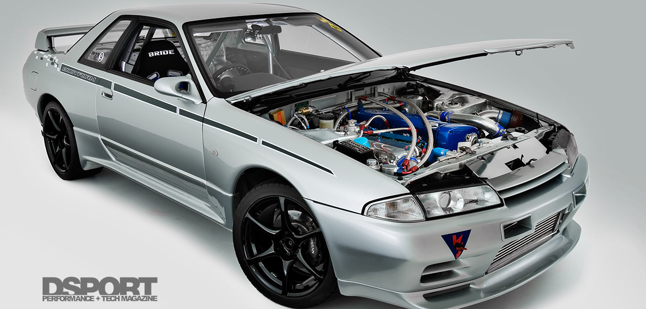 Silver Nissan Skyline R32 with open bonnet displaying modified engine bay, front intercooler, and performance aero kit