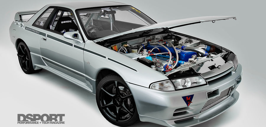 Silver Nissan Skyline R32 with open bonnet displaying modified engine bay, front intercooler, and performance aero kit