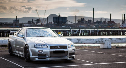 Silver Nissan Skyline R34 with JSAI Aero body kit parked near waterfront front view