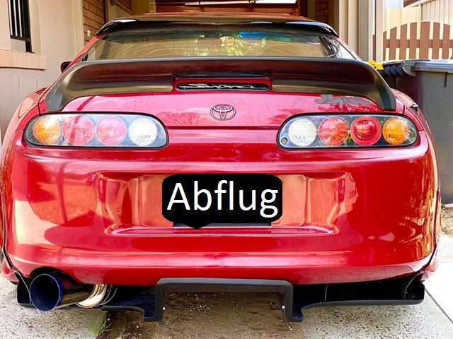 Rear view of red Toyota Supra with aftermarket diffuser and exhaust system, modified performance car with custom rear styling