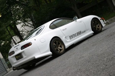White Toyota Supra with aftermarket wheels and side skirts, modified performance car with lowered stance and custom exterior styling